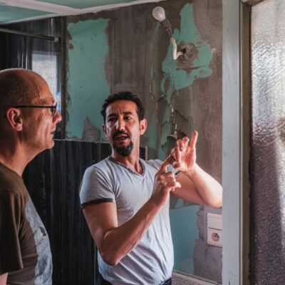 Twee mensen bij een woning in slechte staat.