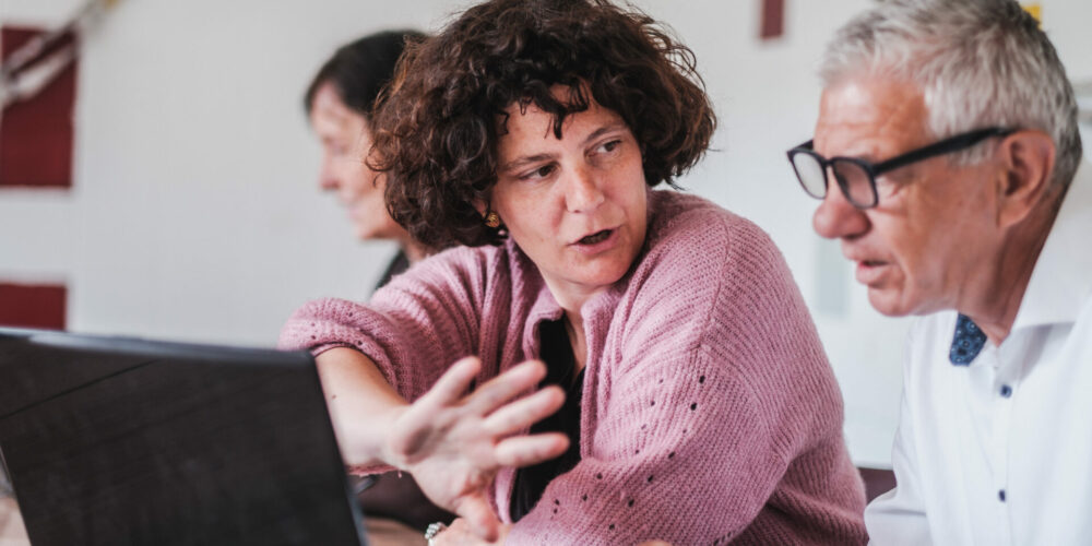 Opbouwwerker Tineke geeft uitleg aan de computer.