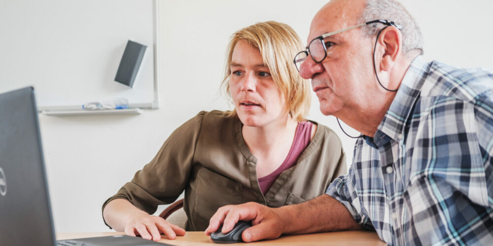 Opbouwwerker geeft uitleg aan computerscherm